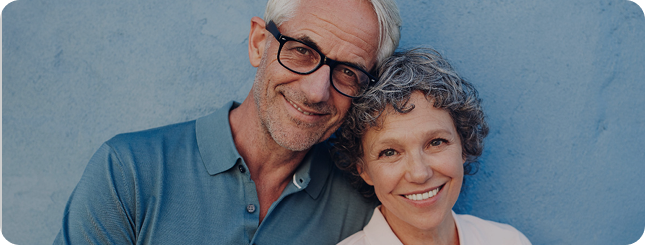 Pärchen vor einer blauen Wand schauen lächend in die Kamera